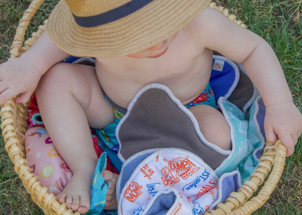 Baby sitting in basket with cloth diapers