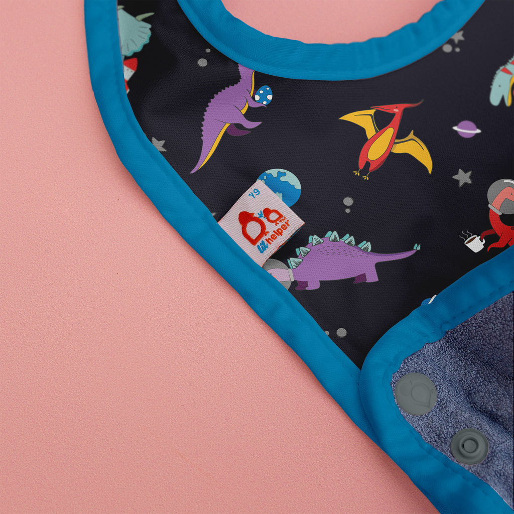 Children's bib with dinosaur pattern on a pink background